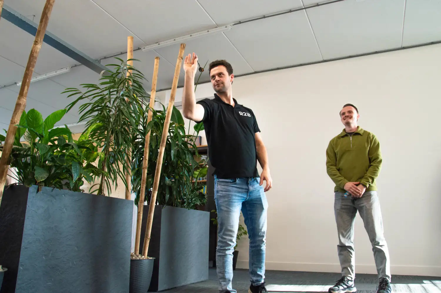 Man met een zwart polo-shirt met wit logo en blauwe jeans