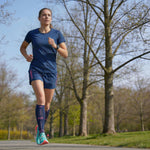 Vrouw hardloopt buiten met R2B elastische kousen blauw.