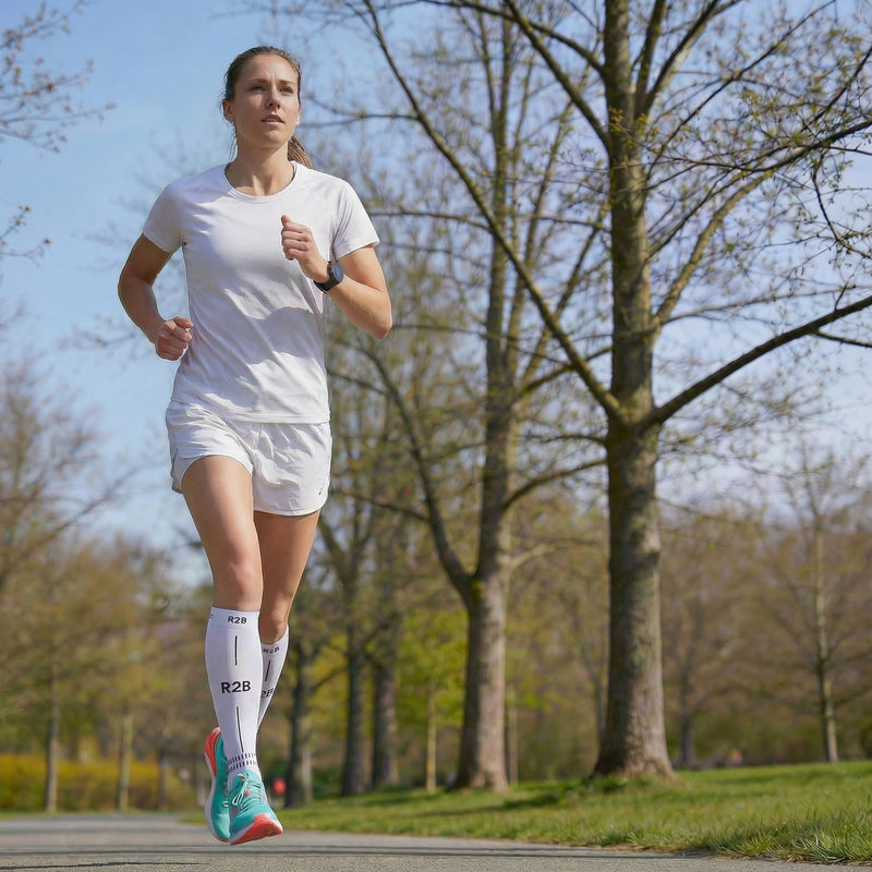 Vrouw hardloopt buiten met R2B elastische kousen wit.