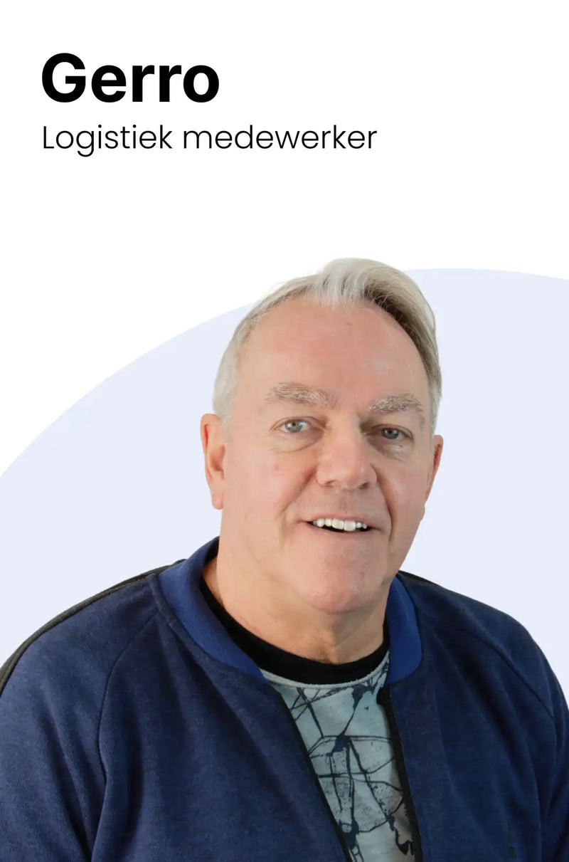 Een man met grijs haar en een vriendelijke glimlach, gekleed in een navyblauwe bomberjack over een zwart-met-grijs patroon t-shirt.