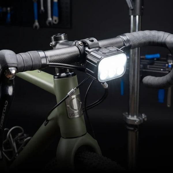 Zwarte rechthoekige fietskoplamp met meerdere felle witte leds en een robuuste, geprofileerde behuizing die op het stuur is gemonteerd.
