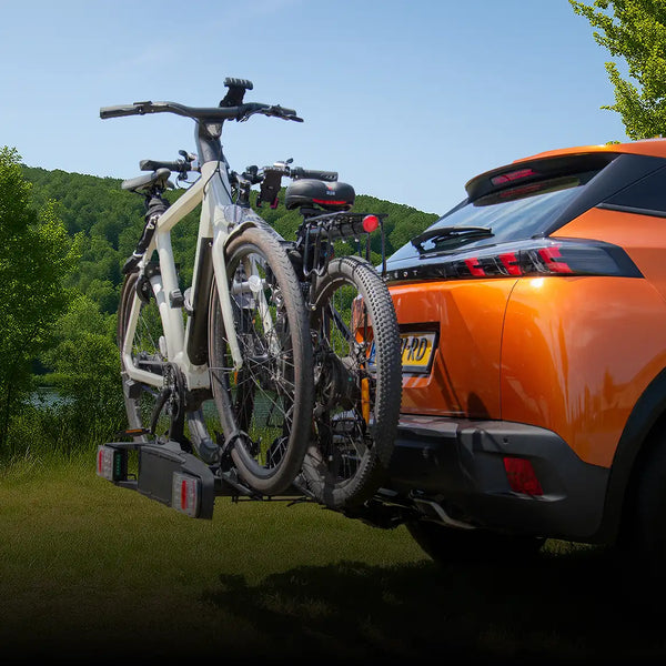 Zwart-zilveren fietsenrek gemonteerd op de achterzijde van een oranje suv.