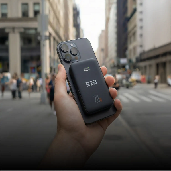 Zwarte r2b draadloze powerbank bevestigd aan de achterkant van een smartphone.